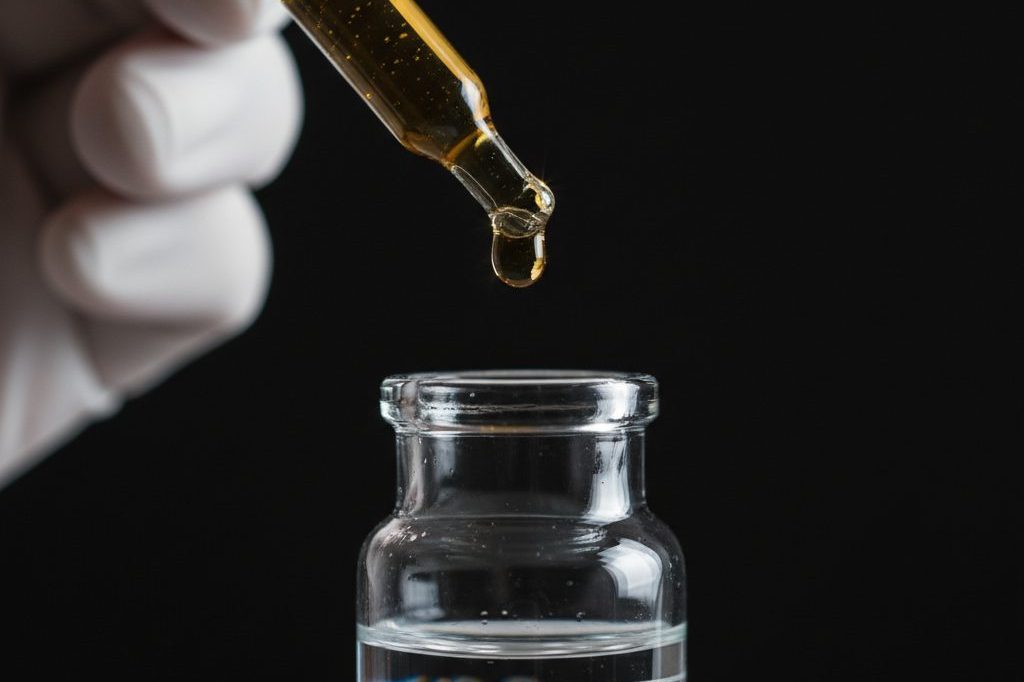 Glass dropper releasing a single droplet into a measuring vial